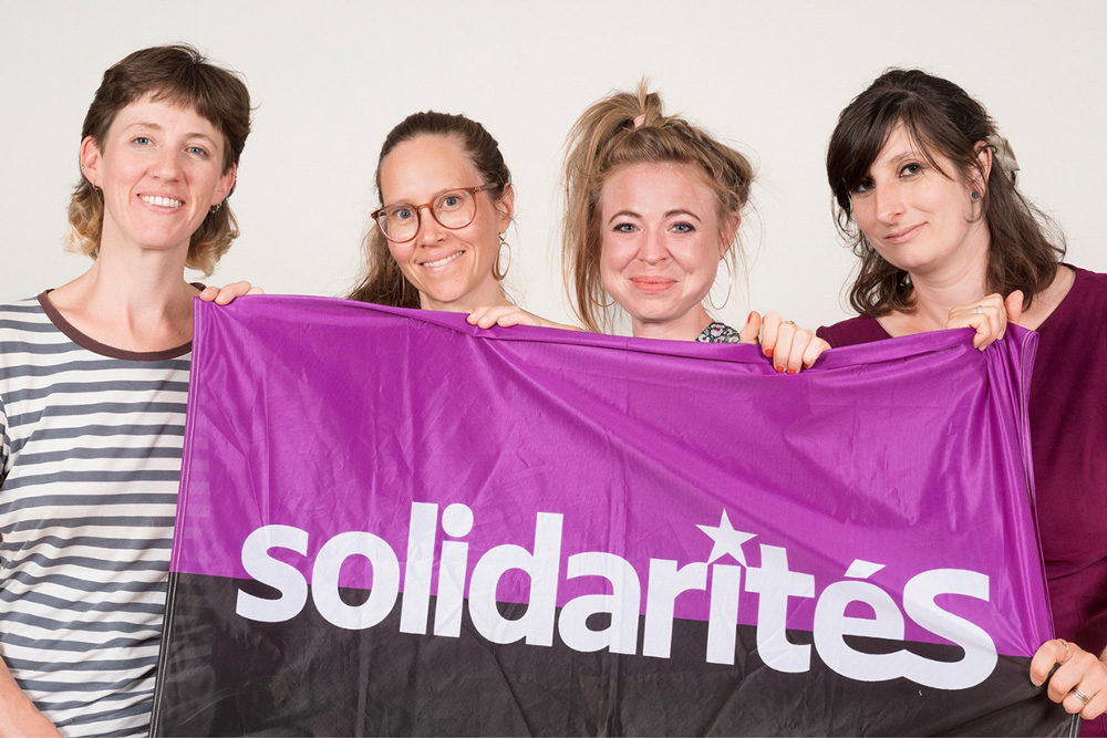 Photo des quatre candidates tenant un drapeau solidaritéS